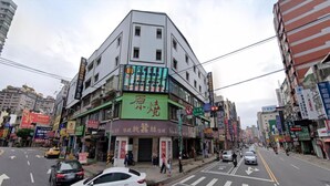 Um edifício de vários andares com fachada verde no andar térreo.
