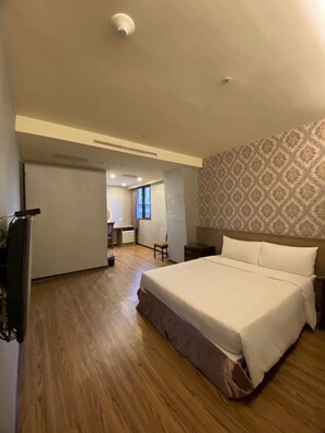 A bedroom with a large bed, a desk, and a chair. - Crystal City Hotel (Taoyuan City)
