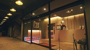 A hotel reception area with a glass door, a reception desk, a telephone, and a sign with contact information. - Crystal City Hotel (Taoyuan City)