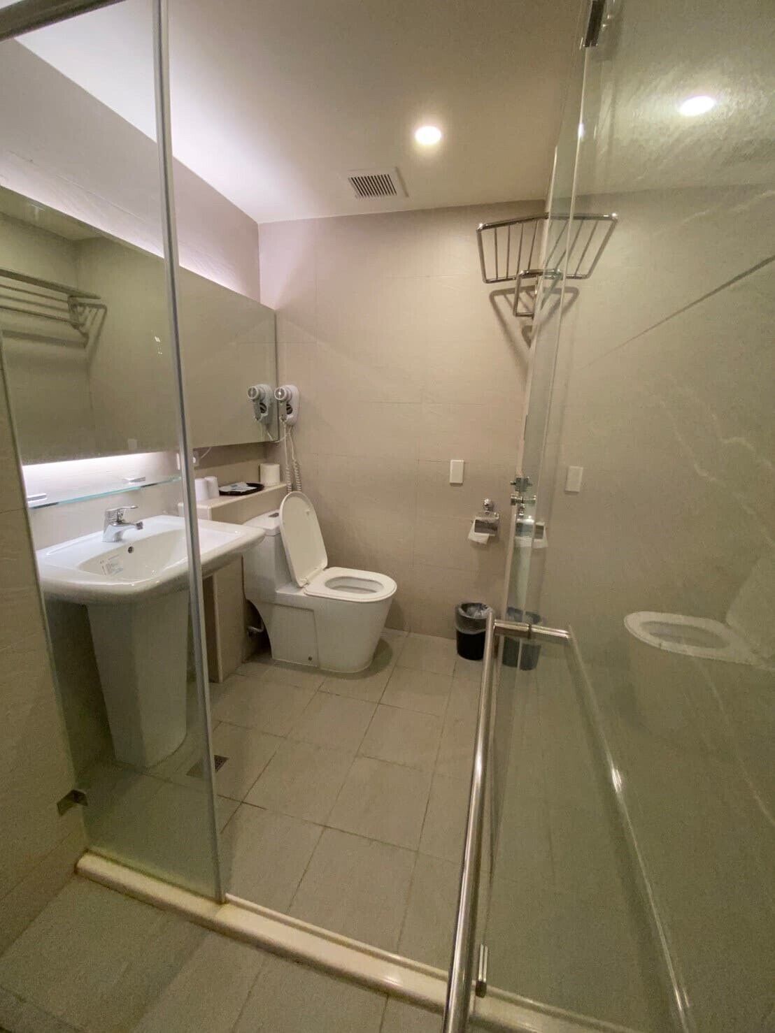 Un baño moderno con cabina de ducha de vidrio, un lavabo blanco y un inodoro.