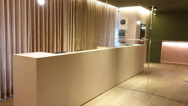 Uma área de recepção com design moderno, com balcão de atendimento, divisória de vidro e um painel de cortina.