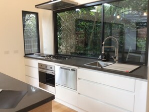 Enjoy cooking in this well-lit kitchen with a large window offering a view of lush greenery.