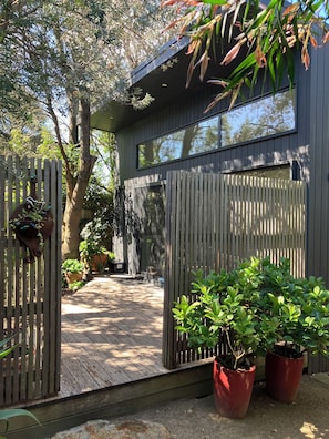 A modern house with a wooden deck, large windows, and potted plants.