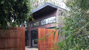 A modern two-story building with a wooden deck and a large glass entrance. - The Twisted Mermaid @ Smiths (Smiths Beach)