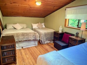 A cozy attic bedroom with two beds, wooden floors, a window with a view, and a small table with a lamp. - Private Chalet - Relax and unwind or recreate to your heart's content (Mount Currie)