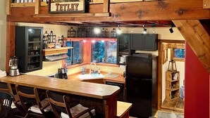 Una cocina con una isla de madera, taburetes de bar, un refrigerador y una ventana con vistas.
