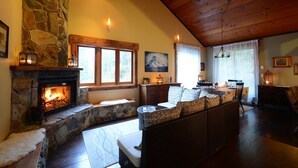 Una sala de estar acogedora con chimenea de piedra, asientos cómodos y un comedor.
