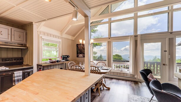 A spacious kitchen with a large island, wooden cabinets, and a view of the outdoors through large windows. - 1 Mi to Beech Mtn Ski Resort: Home w/ Large Yard (Beech Mountain)