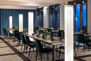 Une salle de conférence avec de longues tables, des chaises et des plantes en pot.