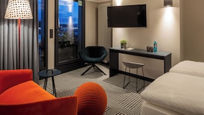 Een moderne hotelkamer met een bed, een bureau, een stoel en een televisie.