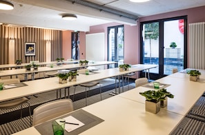A conference room with long tables, chairs, and potted plants. - The Midtown Hotel (Cologne)