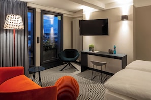 A modern hotel room with a bed, a desk, a chair, and a TV. - The Midtown Hotel (Cologne)