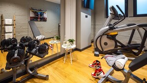 A gym with exercise equipment, a treadmill, and a mirror reflecting the room. - The Midtown Hotel (Cologne)
