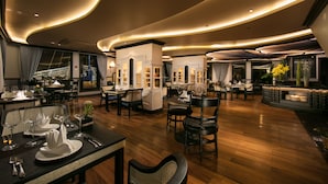 A modern restaurant with wooden flooring, round tables, and black chairs. - Lapinta Luxury Cruises (Hai Phong)
