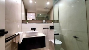 Un baño moderno con lavamanos blanco, inodoro y cabina de ducha de cristal.