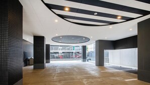 A spacious indoor area with a high ceiling, a central open space, and a view of an outdoor area with a fence and a vehicle. - APA Hotel Fukuoka Tenjin Nishi (Fukuoka)