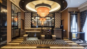 A modern lobby with a central reception desk, a large chandelier, and patterned walls. - APA Hotel Fukuoka Tenjin Nishi (Fukuoka)