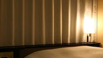 A hotel room with a bed, a nightstand with a control panel, and a lamp.