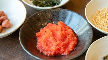 A table with various dishes including a bowl of red food, a bowl of green seaweed, and a bowl of yellow grains.