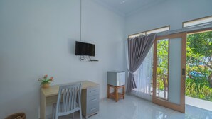 Una habitación con escritorio, silla, televisor y un refrigerador pequeño.