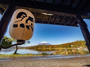 A traditional Japanese lantern hanging over a road with a view of Mount Fuji in the background. - Guesthouse Zen- Hostel (Yamanakako)