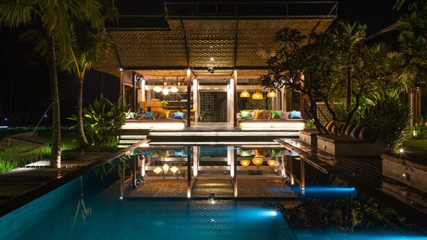 A modern hotel with a pool, outdoor seating, and lush greenery. - Podpadi Design Spaces (Ubud)