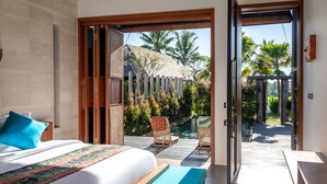 A bedroom with a large bed, a view of a pool, and a wooden deck. - Podpadi Design Spaces (Ubud)