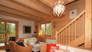 A cozy wooden cabin interior with a dining area, sofa, and wicker chairs. - Almhaus Galisch by Interhome (Sirnitz - Hochrindl)