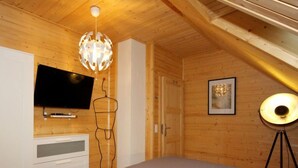 A bedroom with a bed, a TV, a chandelier, and a framed picture on the wall. - Almhaus Galisch by Interhome (Sirnitz - Hochrindl)