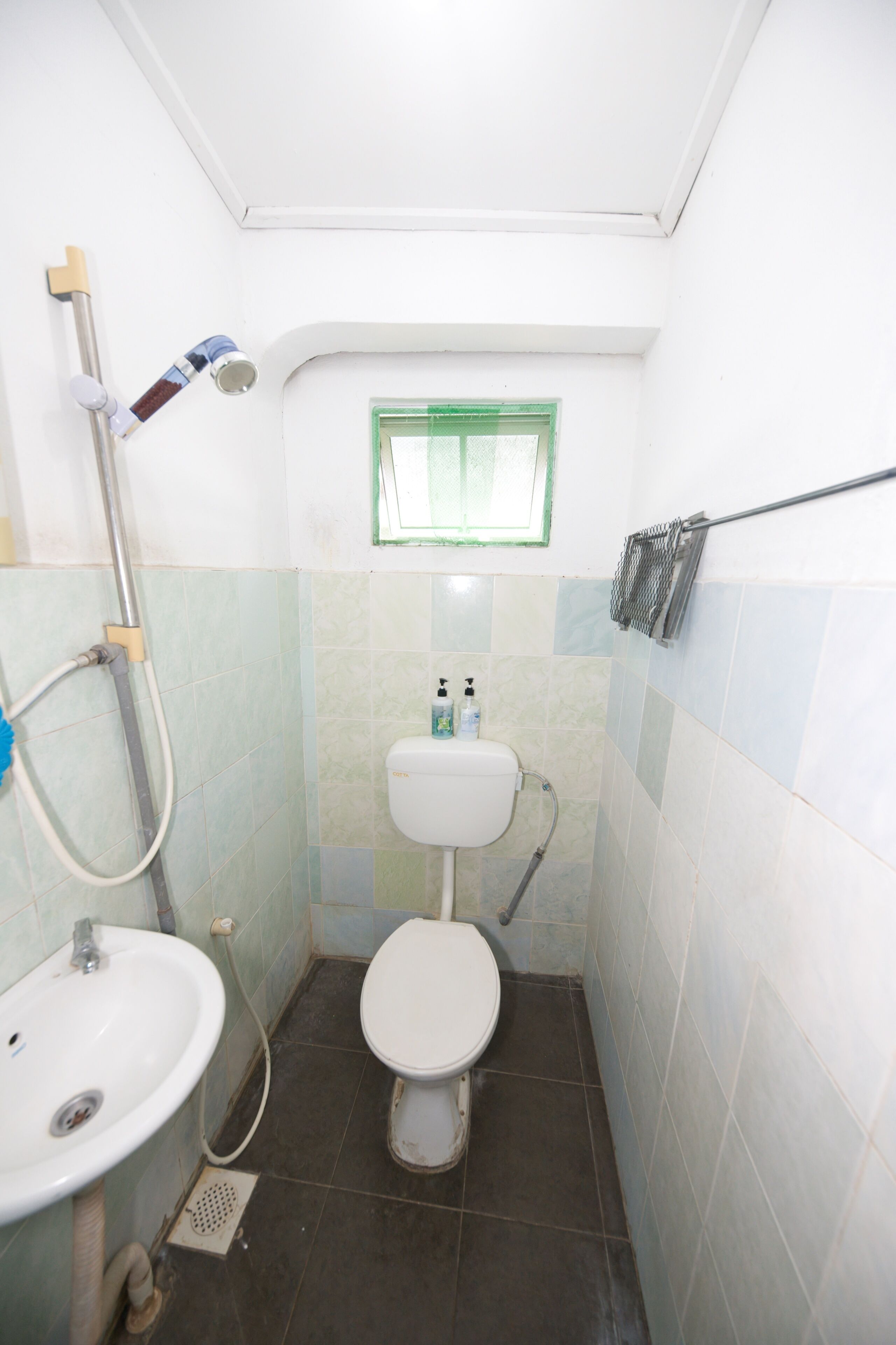 Une petite salle de bain étroite, équipée de toilettes, d’un lavabo et d’une douche.