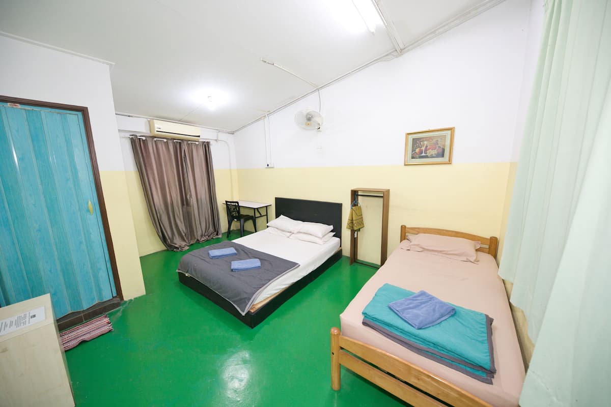 A room with two beds, a desk, a chair, and an air conditioning unit.