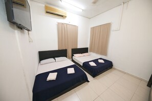 A room with two beds, each with a dark blue bedspread and white pillows. There is a flat-screen TV mounted on the wall, an air conditioning unit above the beds, and a window with beige curtains. - Hotel O Innap Kota Bharu (Kota Bharu)