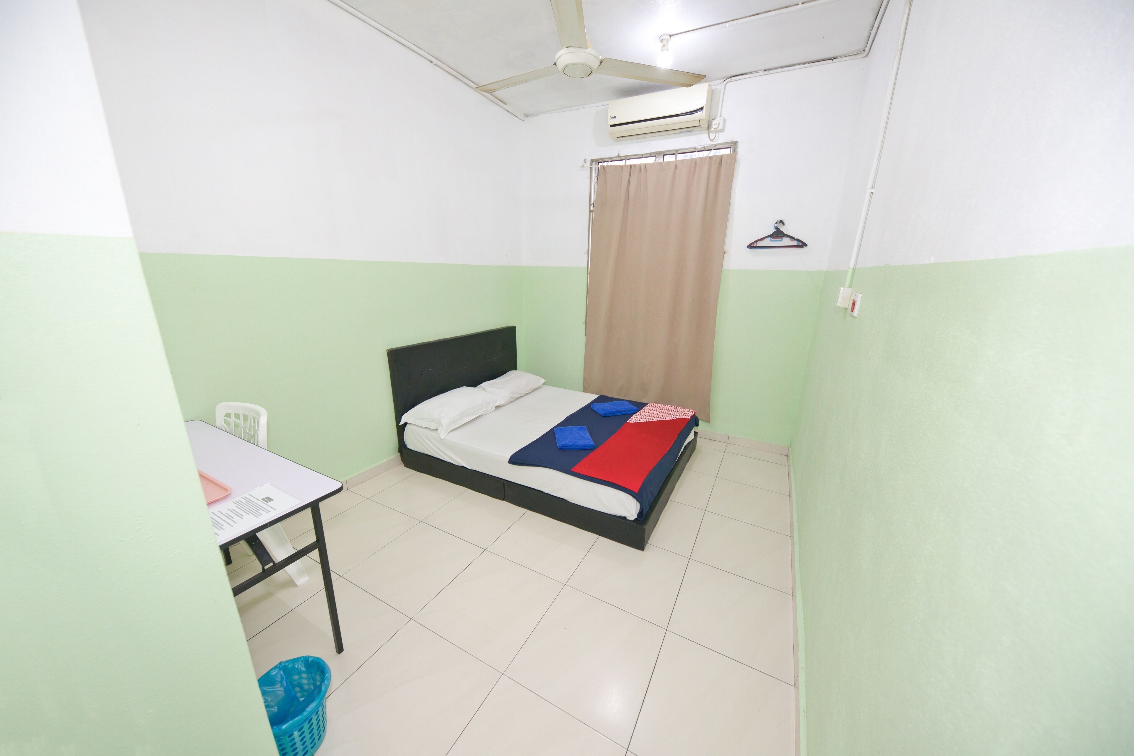 A small, clean room with a single bed, a desk, and a chair.