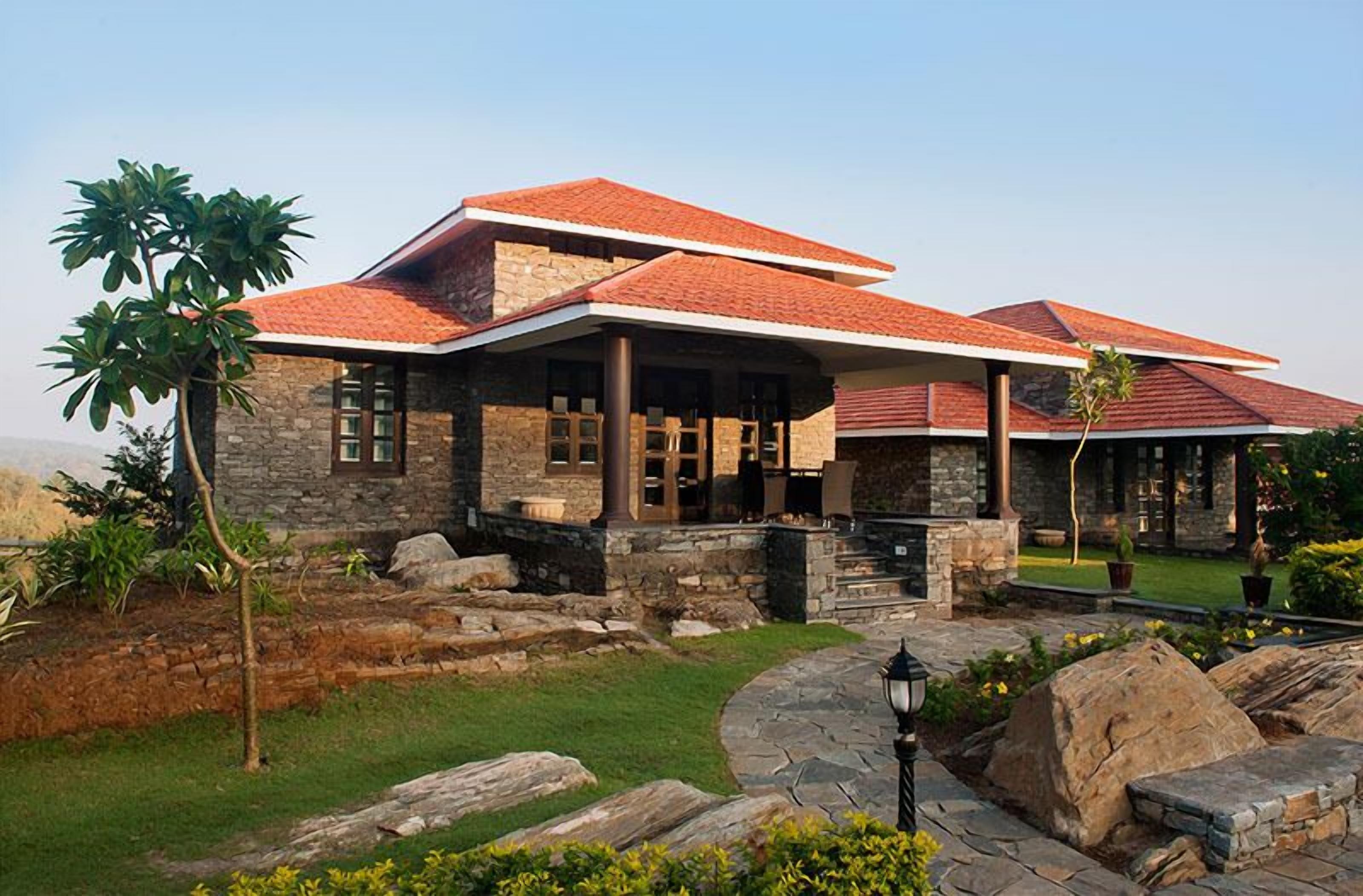 A stone house with a red-tiled roof, a stone patio, and a well-maintained garden.