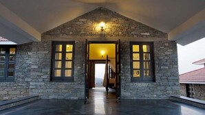 A stone building with a triangular roof and a central doorway leading to a staircase. - The Wild Retreat (Kumbhalgarh)