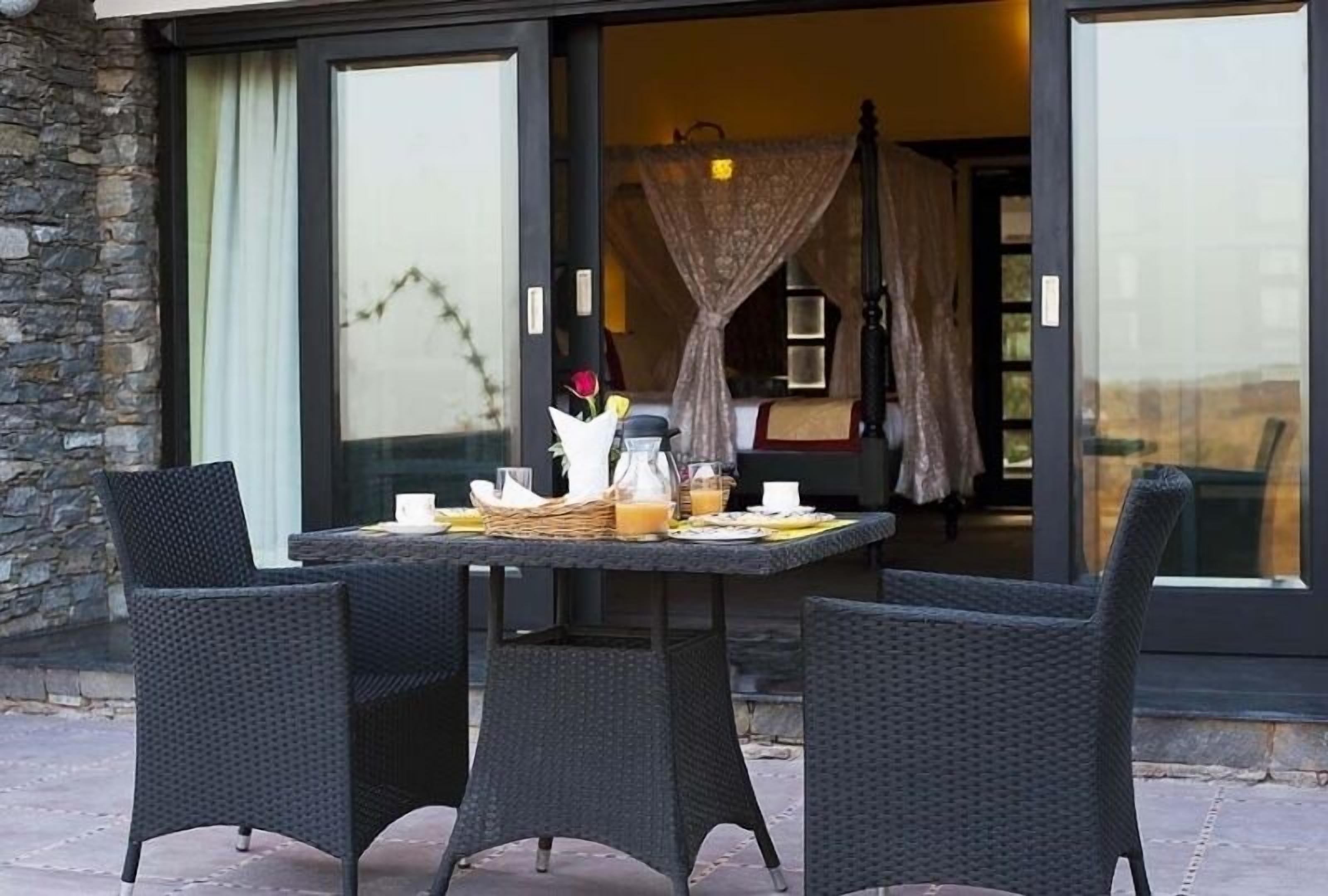 An outdoor dining area with wicker chairs and a table set for breakfast.