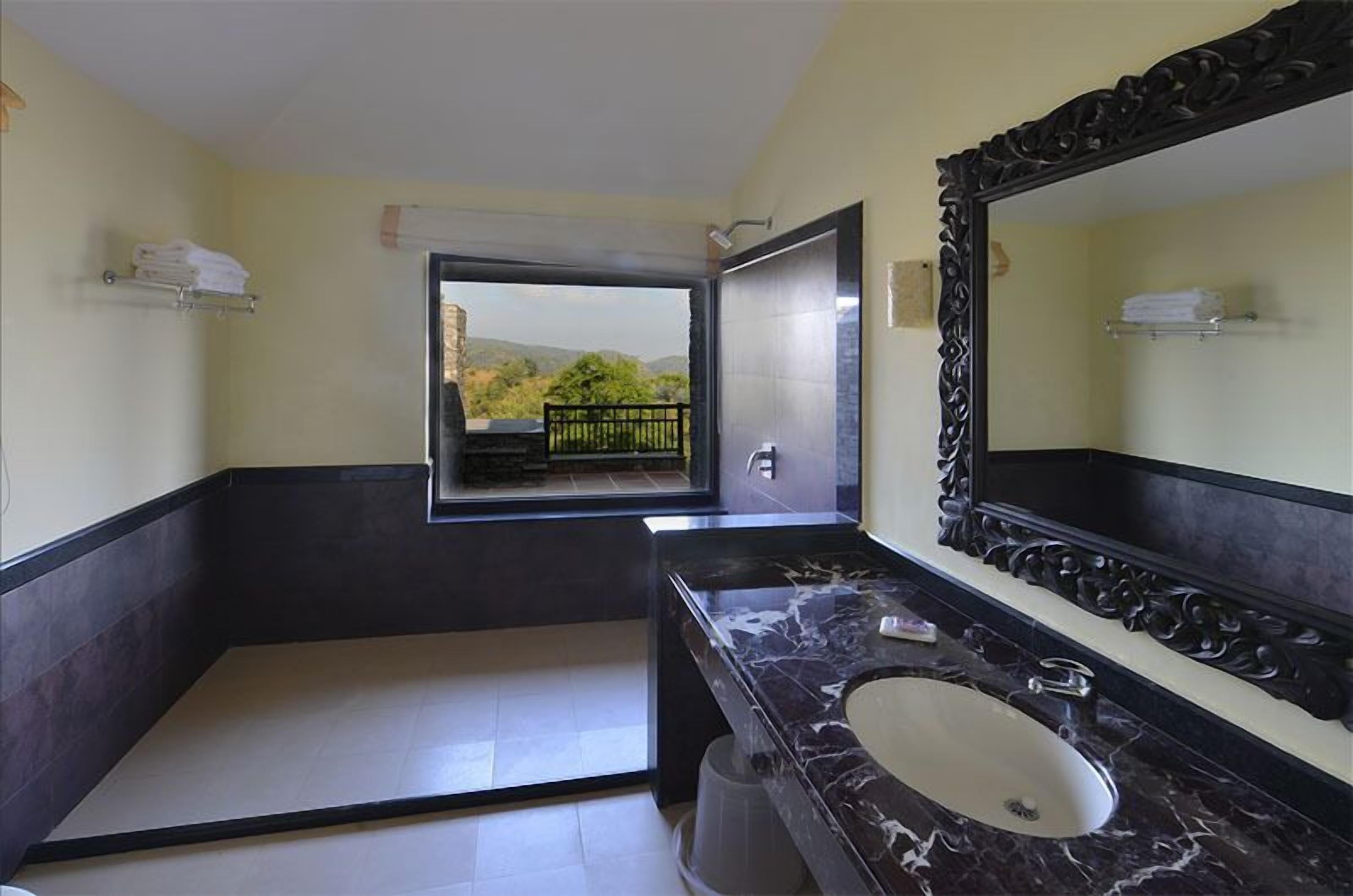 A bathroom with a large mirror, a sink, and a view of a balcony with a railing.
