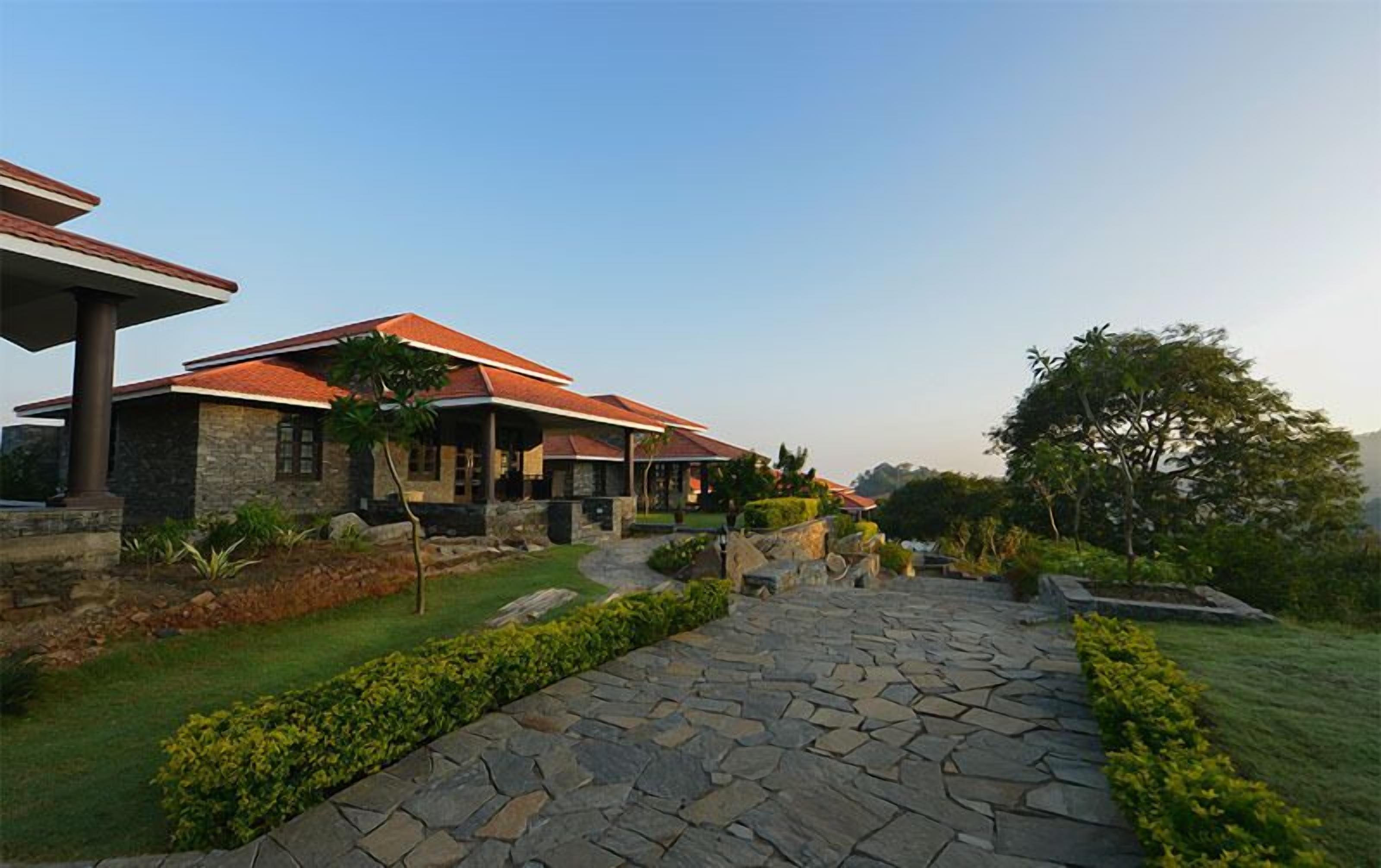 A stone pathway leading to a house with a red roof and stone walls.