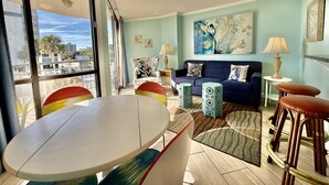 Un salon moderne avec une table ronde, un canapé bleu et un grand tableau abstrait accroché au mur.