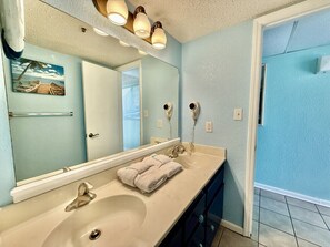 Een bad/douchecombinatie, een haardroger, handdoeken