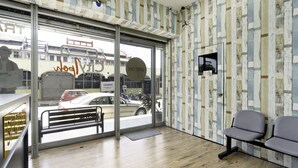 A reception area with a wooden floor, a bench, and a view of the street through large glass doors. - Hotel O City Hostel Ipoh (Ipoh)