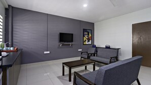 A modern living room with a flat-screen TV, grey sofas, a coffee table, and a ceiling fan. - Hotel O City Hostel Ipoh (Ipoh)