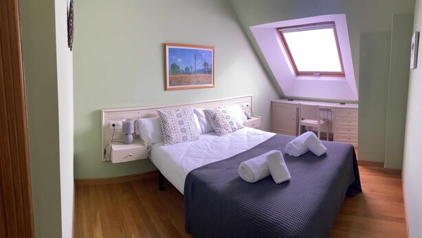 Une chambre à coucher avec un lit, une table de chevet, une lampe et un tableau au mur.