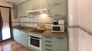 Une cuisine compacte équipée d’un évier, d’une cuisinière, d’un four à micro-ondes et d’une machine à café.