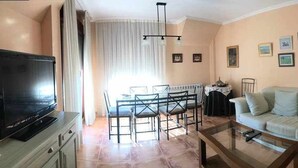 Un salon comprenant un téléviseur, un canapé, une table basse, une table à manger et des chaises.