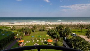 Blick auf einen Strandort mit Poolbereich, Liegestühlen und Sonnenschirmen.