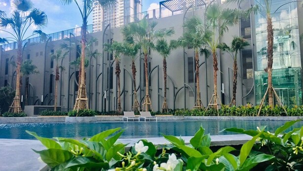 Un edificio moderno con piscina, palmeras y sillones de descanso.