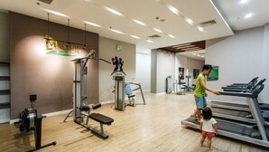 Un gimnasio con equipo de cardio, una prensa de banca y una pared con una cita motivacional.