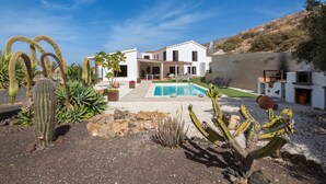 A pool with a white house in the background, surrounded by cacti and rocks. - Air-Conditioned Villa "Selena" with Pool, Garden & Wi-Fi (Pájara)