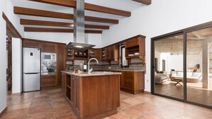 A modern kitchen with wooden cabinets, a stainless steel refrigerator, and a large island. - Air-Conditioned Villa "Selena" with Pool, Garden & Wi-Fi (Pájara)